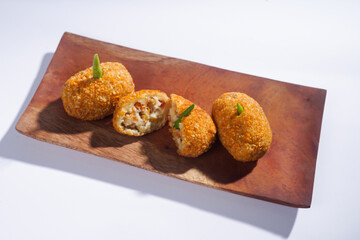 Delicious Indonesian snack named Risol or Risoles filled with smoked beef mayonnaise and crispy fried bread crumb texture on a wooden plate, isolated on a white background