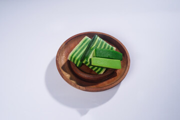 Sticky layer cake or Kue Lapis on wooden plate isolated on white background. Indonesian traditional...