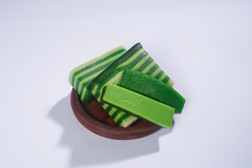 Sticky layer cake or Kue Lapis on wooden plate isolated on white background. Indonesian traditional dessert made from rice flour and coconut milk, steamed layer by layer served on banana leaves. Selec