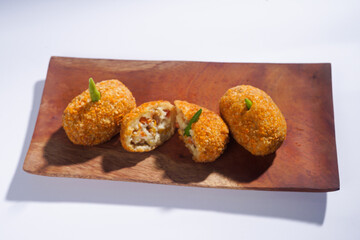 Delicious Indonesian snack named Risol or Risoles filled with smoked beef mayonnaise and crispy fried bread crumb texture on a wooden plate, isolated on a white background