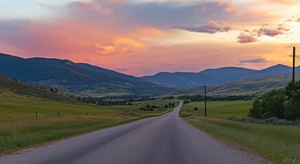 wide road leads into the distance, with green mountains and a blue sky in the background
