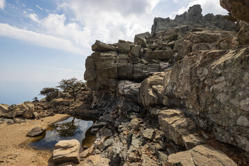 Backpacker sitting at the Selini pool in the rugged mountain range of the wild island of Ikaria.