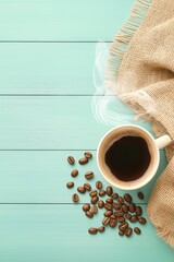 Steaming coffee cup with burlap cloth and coffee beans on mint wooden table