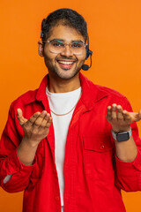 Indian man wearing headset, freelance worker, call center, support service operator helpline, having talk with client or colleague, communication support. Arabian guy isolated on orange background