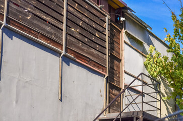 A building with a wooden door and a metal staircase. The door is open and the staircase is made of metal.