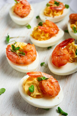 Boiled eggs stuffed with yolk and seasoned with mayonnaise, stuffed eggs with shrimp, on a white wooden chopping board, selective focus, close-up, without people,