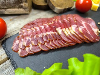 Thin slices of bacon lie on a sliced board