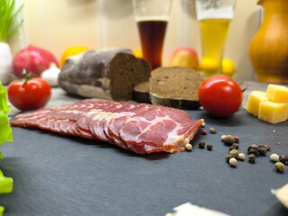 Thin slices of bacon lie on a sliced board in the background of a beer tank