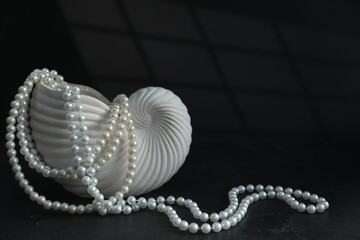 Stylish vase and elegant pearl jewelry on black background, space for text