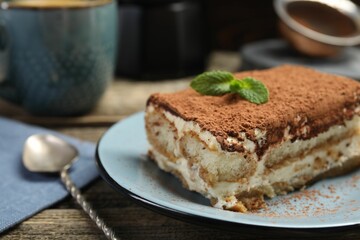 Piece of tasty tiramisu on wooden table, closeup