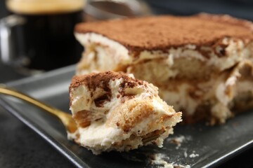 Eating tasty tiramisu at black table, closeup