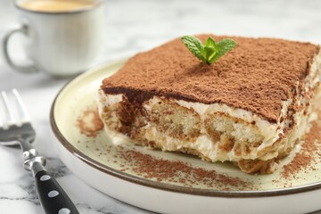 Piece of tasty tiramisu on white marble table, closeup