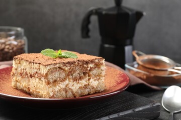 Delicious tiramisu with mint on table, closeup