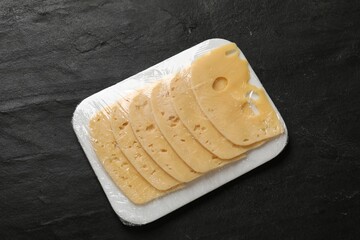 Pack of sliced cheese on black table, top view