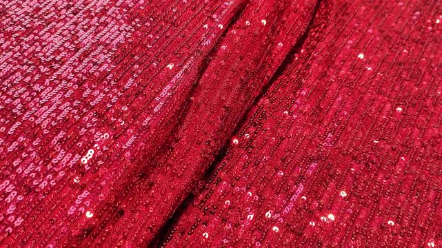 Vibrant red sequin fabric with shimmering highlights and gentle folds for a luxurious, textured effect