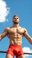 Physical education sports movement concept. A strong athlete confidently poses outdoors under a clear blue sky, showcasing impressive muscle definition and fitness.
