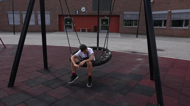 Upset teenager with mental disability playing alone in the schoolyard. Boy with autism Asperger syndrome having leisure outdoor