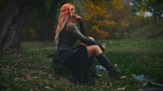 fantasy woman warrior queen holding two sharp knife blade dagger. Sexy girl elf in dark night forest sitting by river water stream nature tree. Black leather dress. lady beauty sexy face blond hair