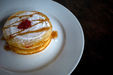 Delicious pancake with honey syrup and sprinkled with white sugar powder on white plate