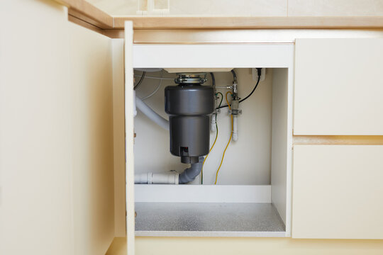 The installation of a functional garbage disposal unit beneath the kitchen sink showcases essential plumbing setup.