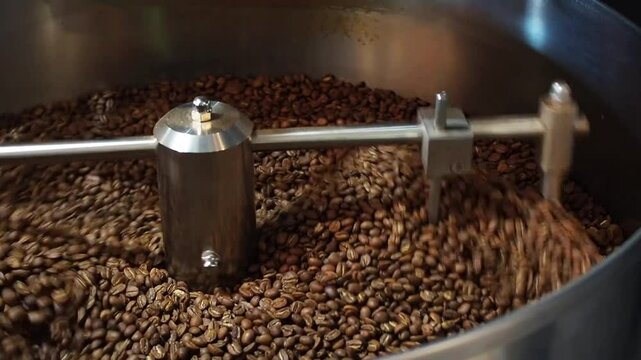 Process of roasting coffee beans in a drum machine in close-up. Production of delicious and fragrant coffee
