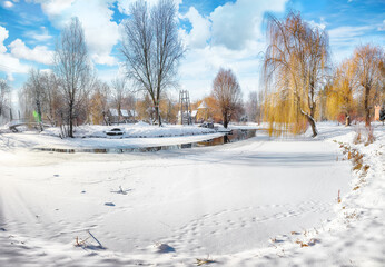Stunning landscape with snowy trees, beautiful frozen river with reflection in water.