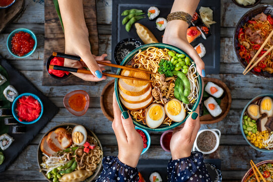 Ramen noodles at the hands of two women. Tonkotsu ramen bowl. 