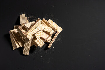 A pile of wafers on a black background. The wafers are in different shapes and sizes, and they are scattered all over the surface. Concept of abundance and variety