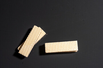 A close up of a few pieces of wafers on a black background. The wafers are white and appear to be square in shape