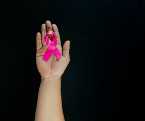 Hand holding pink ribbons on black background. World epilepsy day. Alzheimer's disease, Pancreatic cancer, Epilepsy awareness, fibromyalgia awareness.