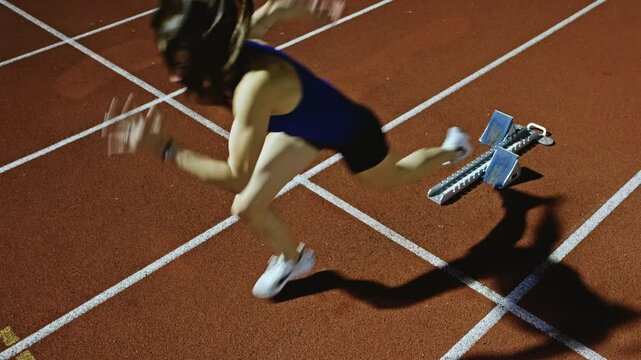 Female Runner on Athletics sprint race starting blocks on a dark background