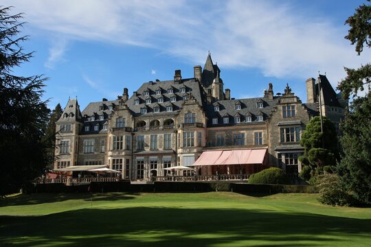 Castle Hotel Kronberg behind trees and grassy area in Kronberg im Taunus on a sunny day