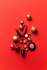 Vibrant holiday makeup arranged with shiny ornaments on a bold red background, perfect for festive beauty promotions.