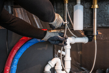 Plumber attaches faucets to the kitchen sink