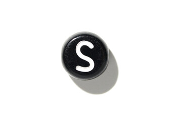 Black round salt shaker with white letter s casting shadow on a white background in minimalist style