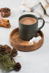 Hot chocolate mug and small marshmallows on wooden saucer