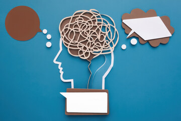 A creative illustration of a human head with a tangled brain and speech bubbles, depicting mental health, communication, and the complexity of thoughts and emotions, copy space