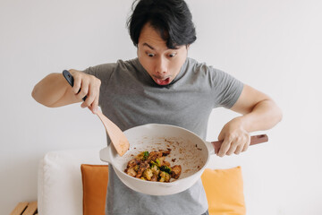 Happy asian man proud and present his homemade meal in the pan.