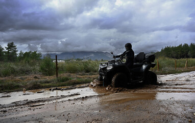 Offroad with an ATV in the forest, mud and puddles after the rain