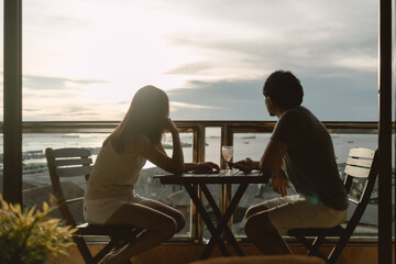 Asian lover couple having dinner enjoy date at private terrace on evening ocean
