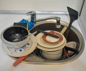 Dirty kitchenware, plates and mugs. Pile of unwashed, dirty dishes in the sink. Mess in the...
