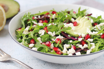 A plate with green rocket salad with pomegranate and avocado