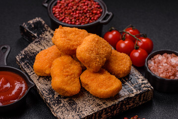 Delicious fresh crispy chicken nuggets on a dark concrete background