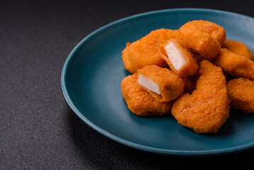 Delicious fresh crispy chicken nuggets on a dark concrete background