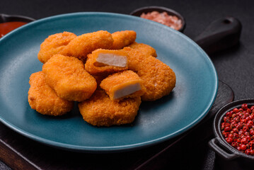 Delicious fresh crispy chicken nuggets on a dark concrete background