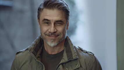 Portrait of a smiling man in his 50s wearing a military coat, showing experience and confidence, happy smiling.