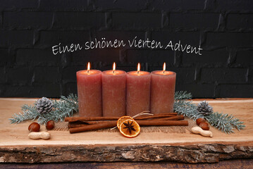 Vierter Advent: Adventskranz vor einer schwarzen Steinmauer mit braunen Kerzen, Weihnachtsschmuck...
