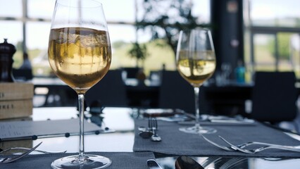 Two refreshing cocktail with ice cube in wine glass standing on table in fancy restaurant waiting for guests to arrive.