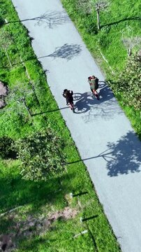 Vertical video of cyclists - High-quality aerial shot of cyclists using electric bikes on a sunny day, captured by drone