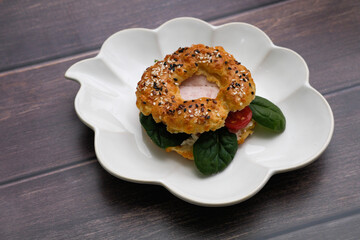 Breakfast bagels with egg, green on wooden table.